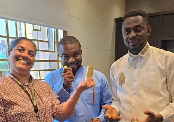Star Gold team members holding certified gold bars in the Accra office