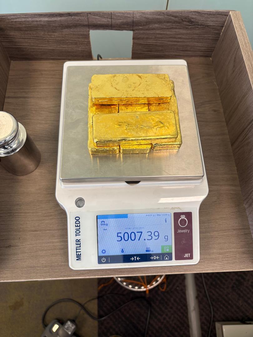Gold bars being weighed and certified on a calibrated digital scale